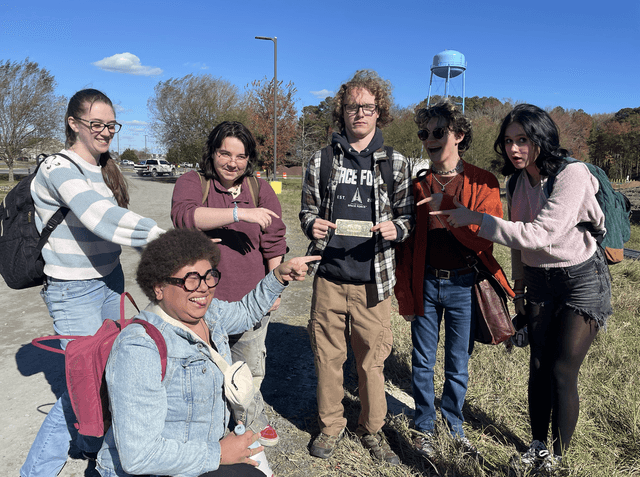 Hen & Ink members celebrating a geocaching find, 2025